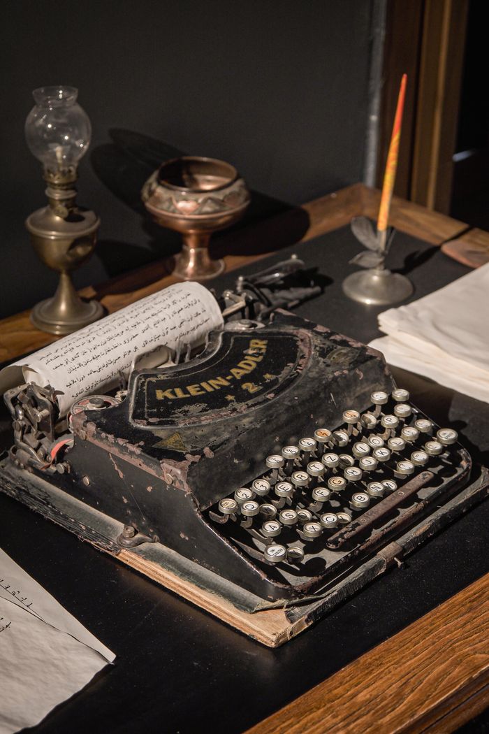 Old Klein Adler typewriter on display with antique lamp and ink pen, evoking nostalgia.